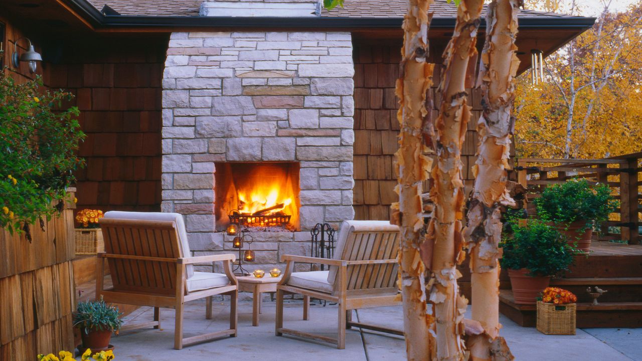 stone built outdoor fireplace ideas in a paved backyard