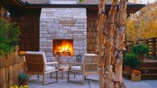 stone built outdoor fireplace ideas in a paved backyard