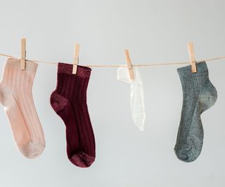 Four odd socks hanging on a line with pegs