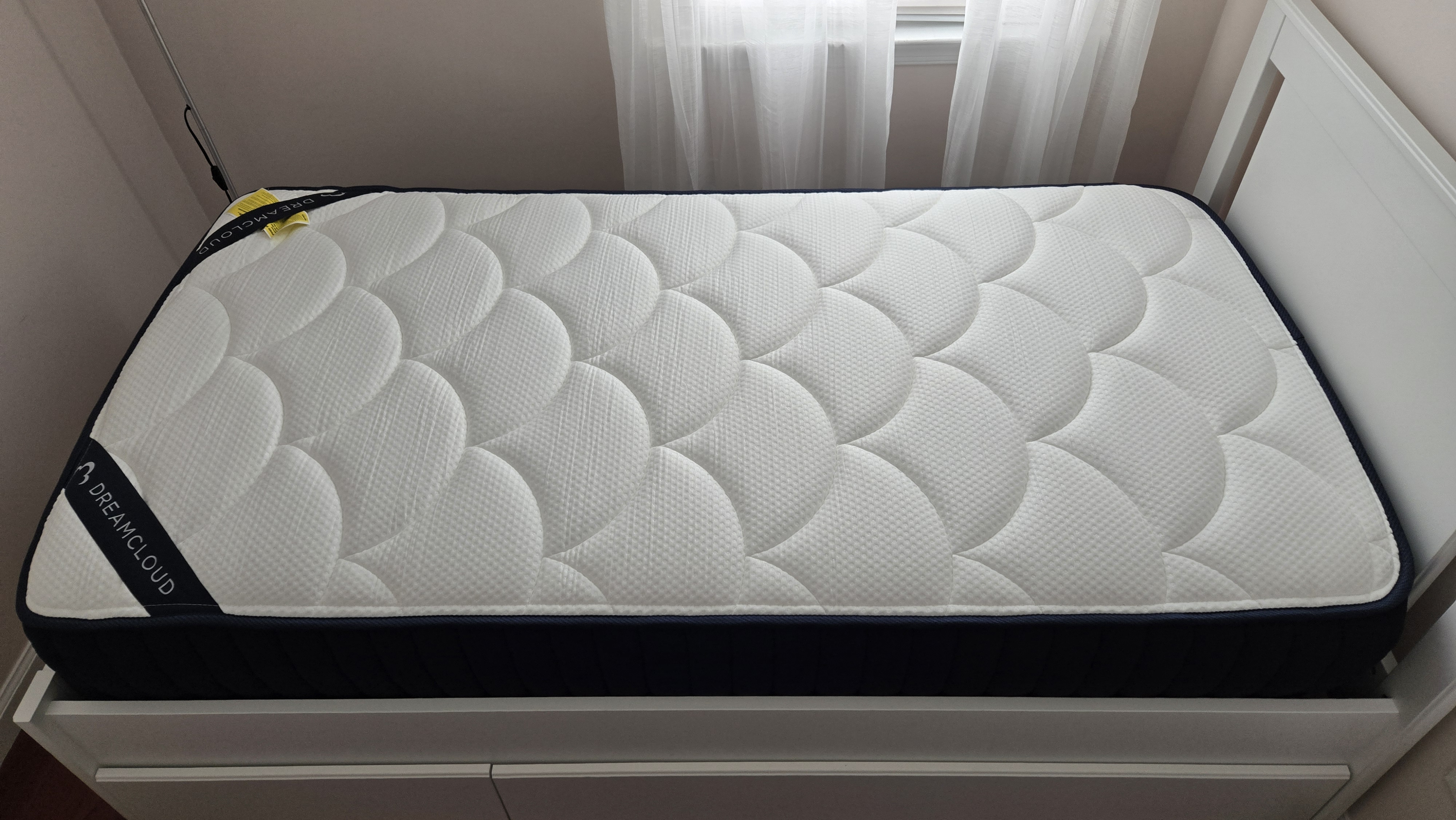 DreamCloud Classic Memory Foam Mattress on a white platform bed, right after it's been unboxed