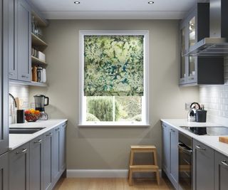 roller blind with real life images of greenery on window at end of small grey kitchen