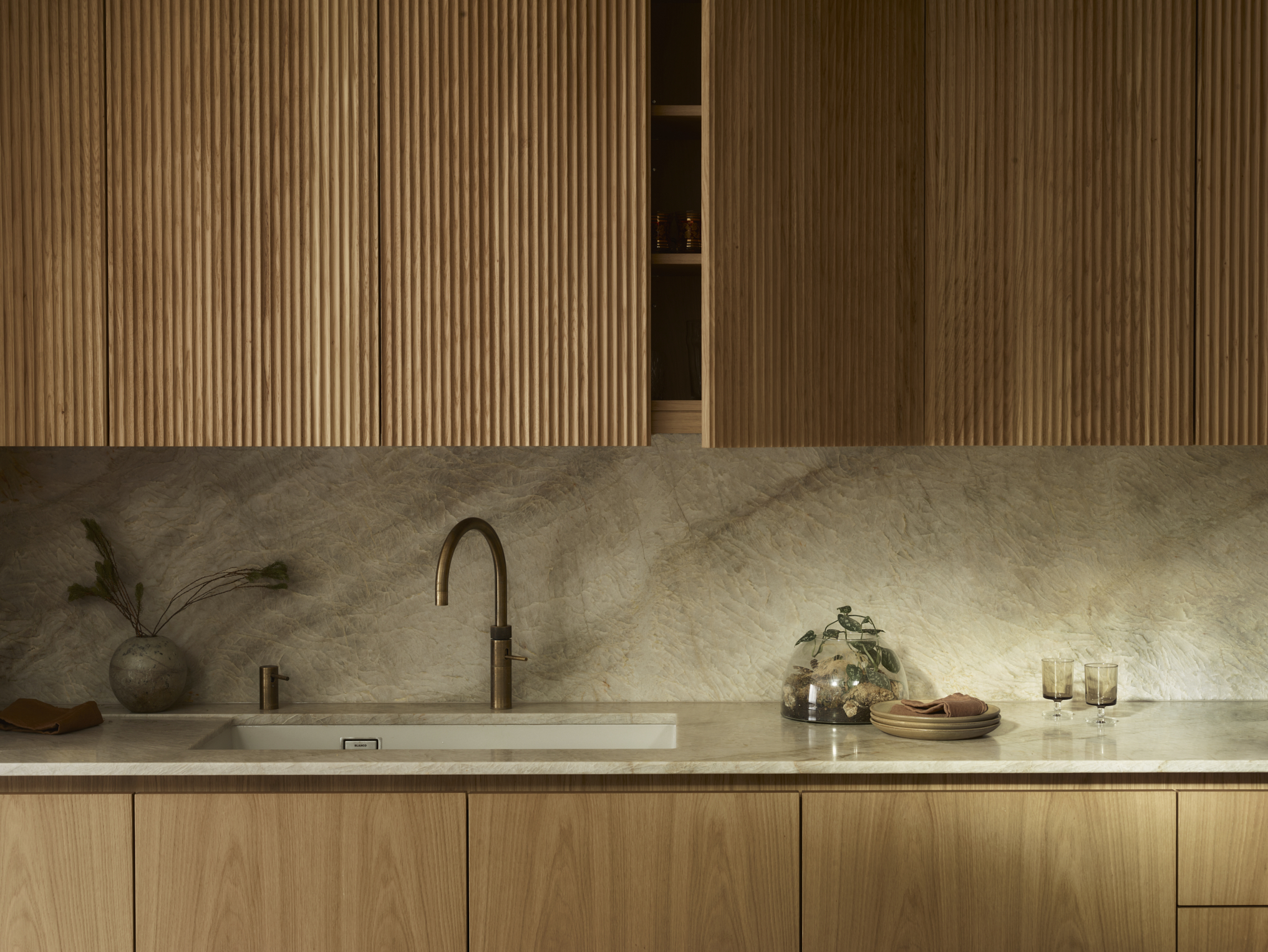 A kitchen with wooden cabinets, upper and lower, with no handles