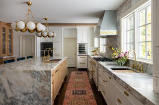 A kitchen with a long runner, and marble island