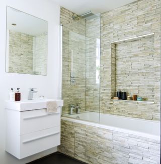 bathroom with white and brick tile wall bathtub and wash basin