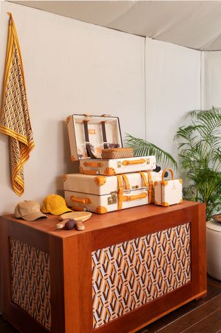 A wooden table with a pile of suitcases on top and a few caps