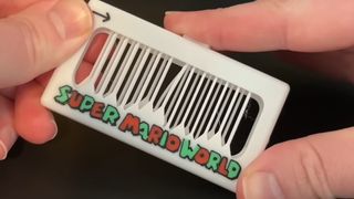 A 3D-printed musical fidget toy that plays the Super Mario World theme being held in the hands