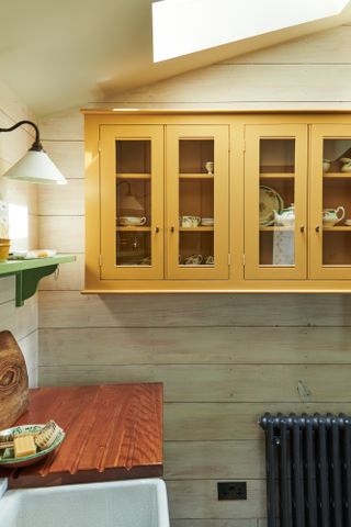 Yellow cabinets with glass windows, wooden surface top