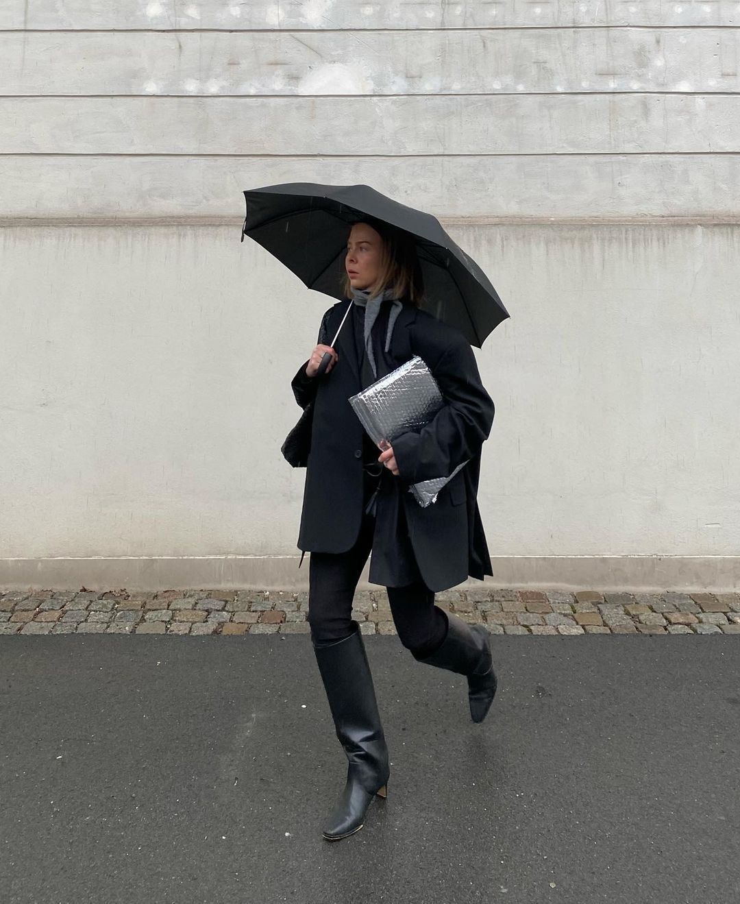 @dinahansen in the rain holding an umbrella