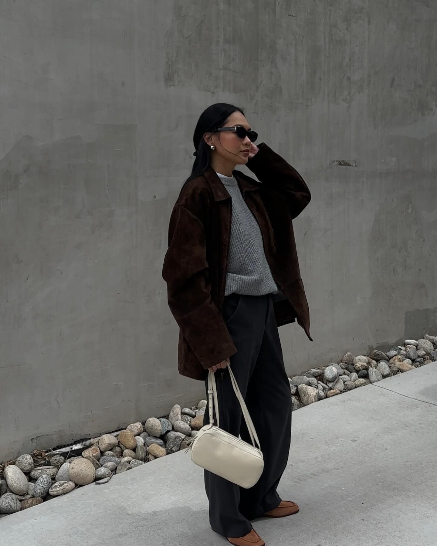 Influencer @dawn.tan wears slouchy jeans with tan suede loafers, a grey jumper and a brown suede leather jacket.