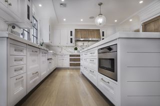 A white kitchen with wooden floors and inset cabinets