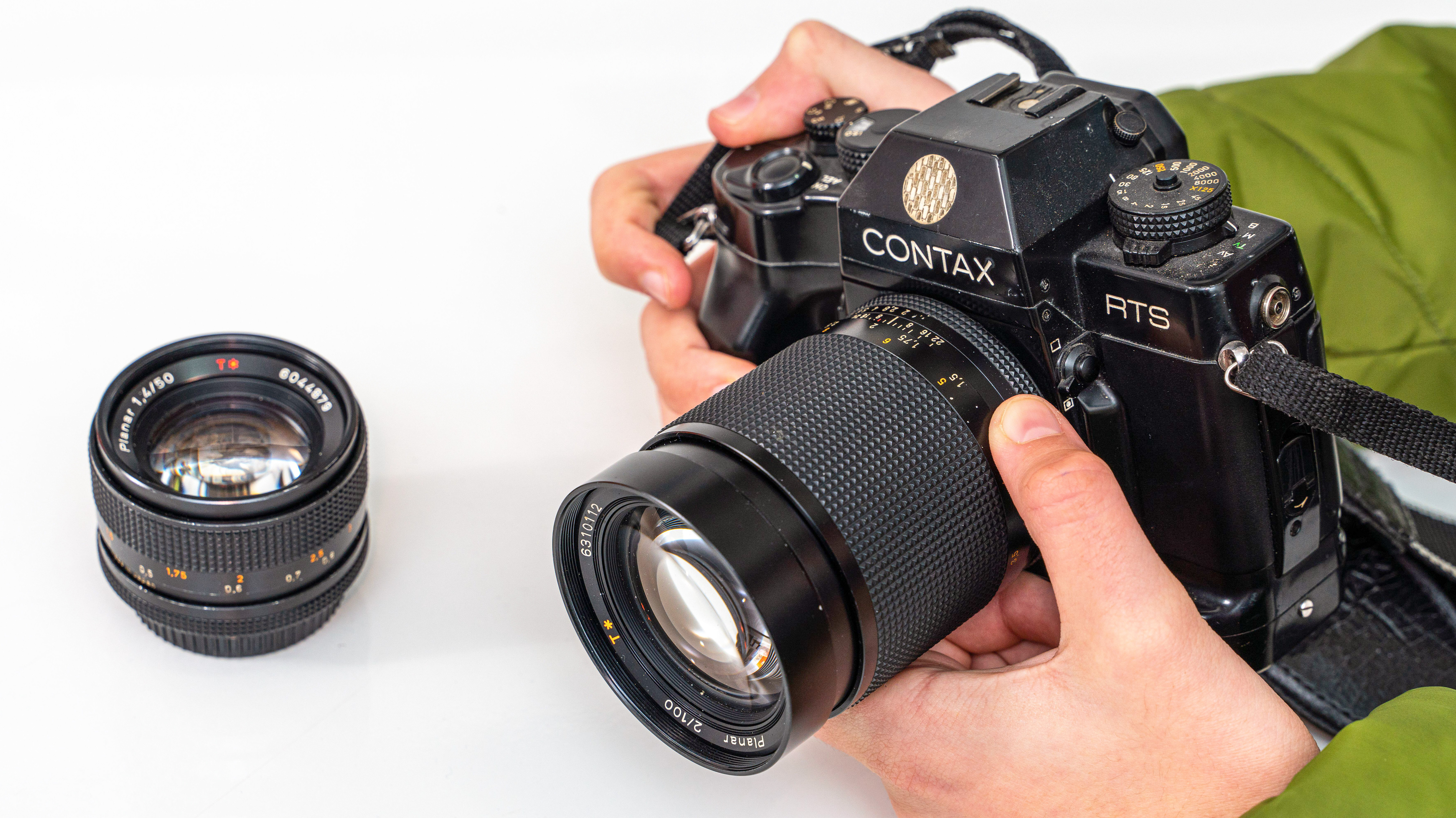 Contax RTS being held in boy's camera with another lens on the table to the side