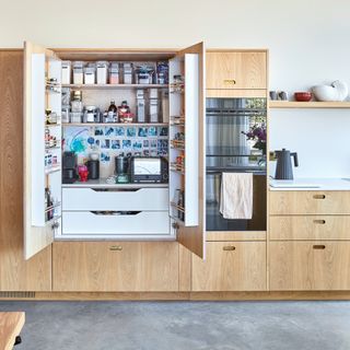 a row of wooden kitchen cabinets with open pantry doors with a breakfast station