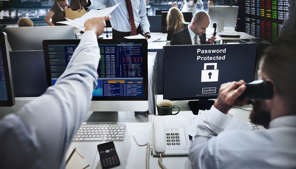 Two desks on a business trading floor, one with computer monitor displaying &#039;Password Protected.&#039;