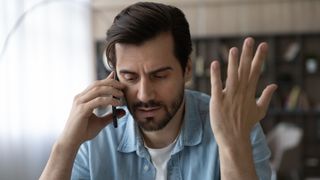 A man making a phone call and looking confused