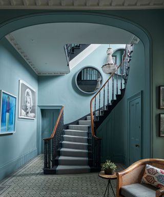 hallway with blue wainted walls and staircase that curves up and tiled floor