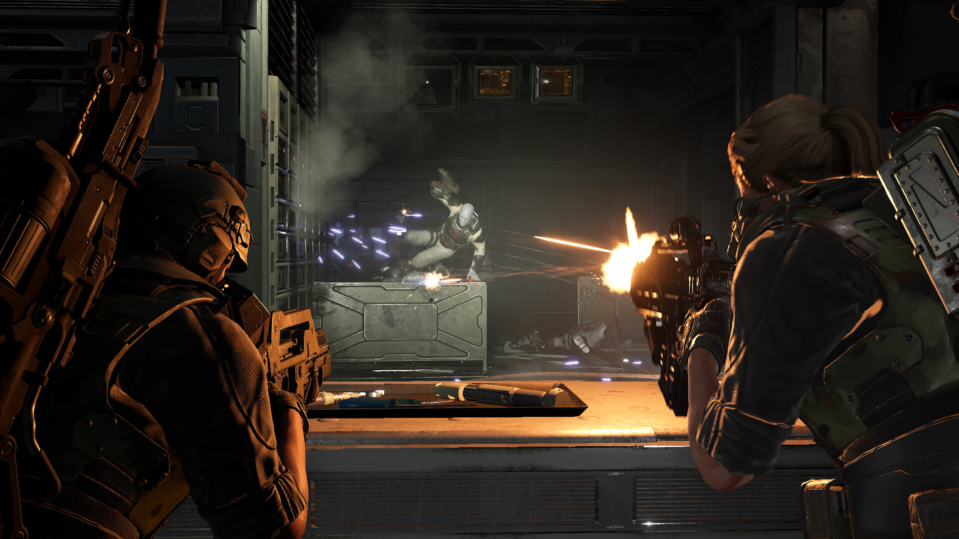 Two futuristic soldiers, a man and a woman, shoot an alien creature in a dark industrial environment. The scene is tense and action-packed.