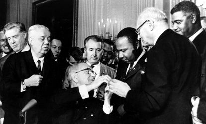 President Johnson shakes hands with Dr. Martin Luther King Jr. after presenting King with one of the 72 pens used to sign the Civil Rights Act of 1964 on July 2, 1964. 