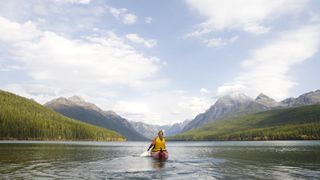 A woman kayaking on a lake in Glacier National Park