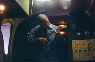 Neil Armstrong plays the ukulele while in the MQF during post-splashdown quarantine.