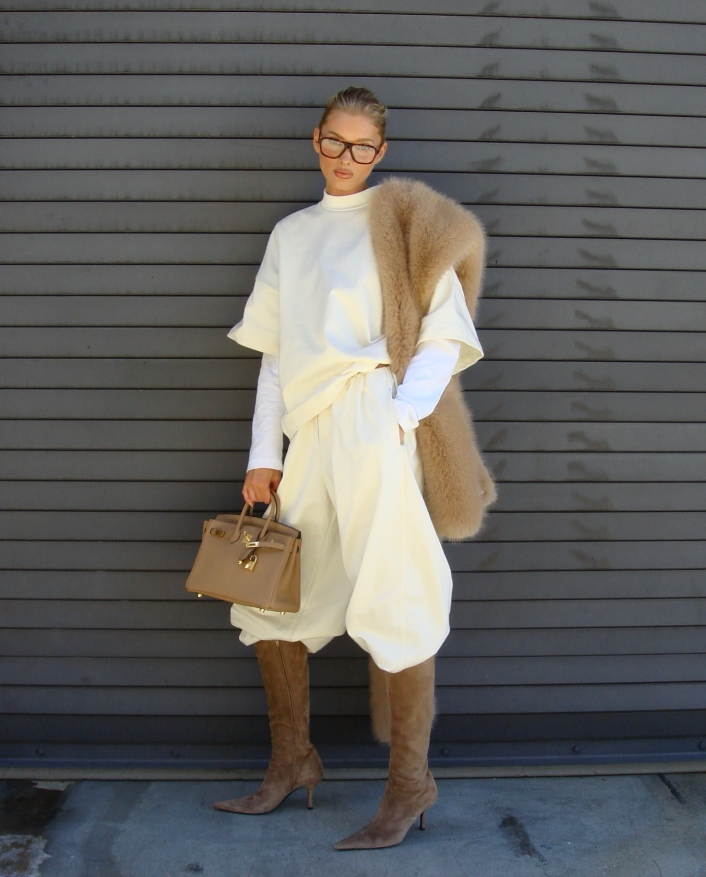 Elsa Hosk wearing a butter yellow sweatshirt and sweatpants with tan boots, a tan fur scarf, and a tan Birkin bag.
