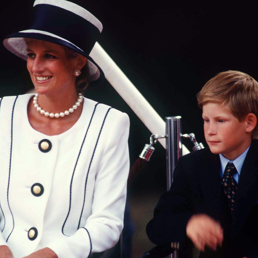 Prince Harry sitting next to Princess Diana, wearing a white blazer and blue hat