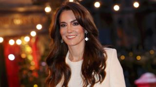 photo of catherine, princess of wales smiling at event wearing a white suit and silver earrings