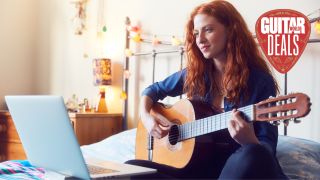 A young woman plays acoustic guitar in front of a laptop