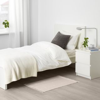 A bedroom with a small beige rug by the side of the bed