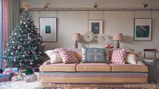 Cream living room with colorful striped sofa and large christmas tree