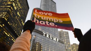 A protestor outside Trump Tower holds a rainbow colored sign that reads, "Love trumps hate."