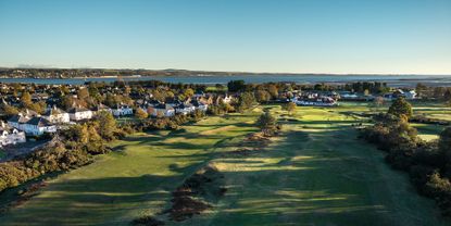 Two holes, the clubhouse and sea pictured from a drone shot of Scotscraig Golf Club
