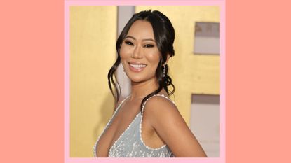 Kelly Mi Li smiling and wearing a silver, sparkly dress as she attends the 19th Annual Unforgettable Gala at The Beverly Hilton on December 11, 2021 in Beverly Hills, California. On an orange and pink background