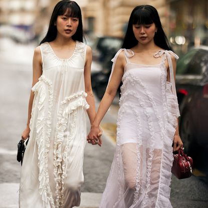 two attendees at paris spring 2025 fashion week wearing white ruffled dresses