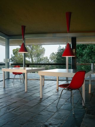 Two white tables with red chairs and red lamp