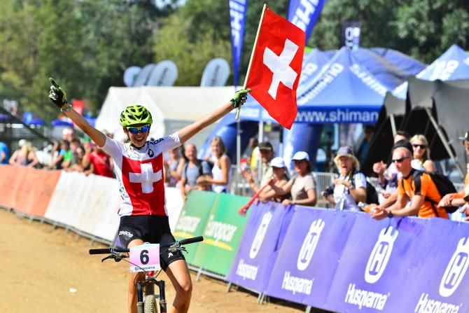 Alessandra Keller proudly wave's the Swiss flag as she cruises to victory in the Junior Women's Cross Country