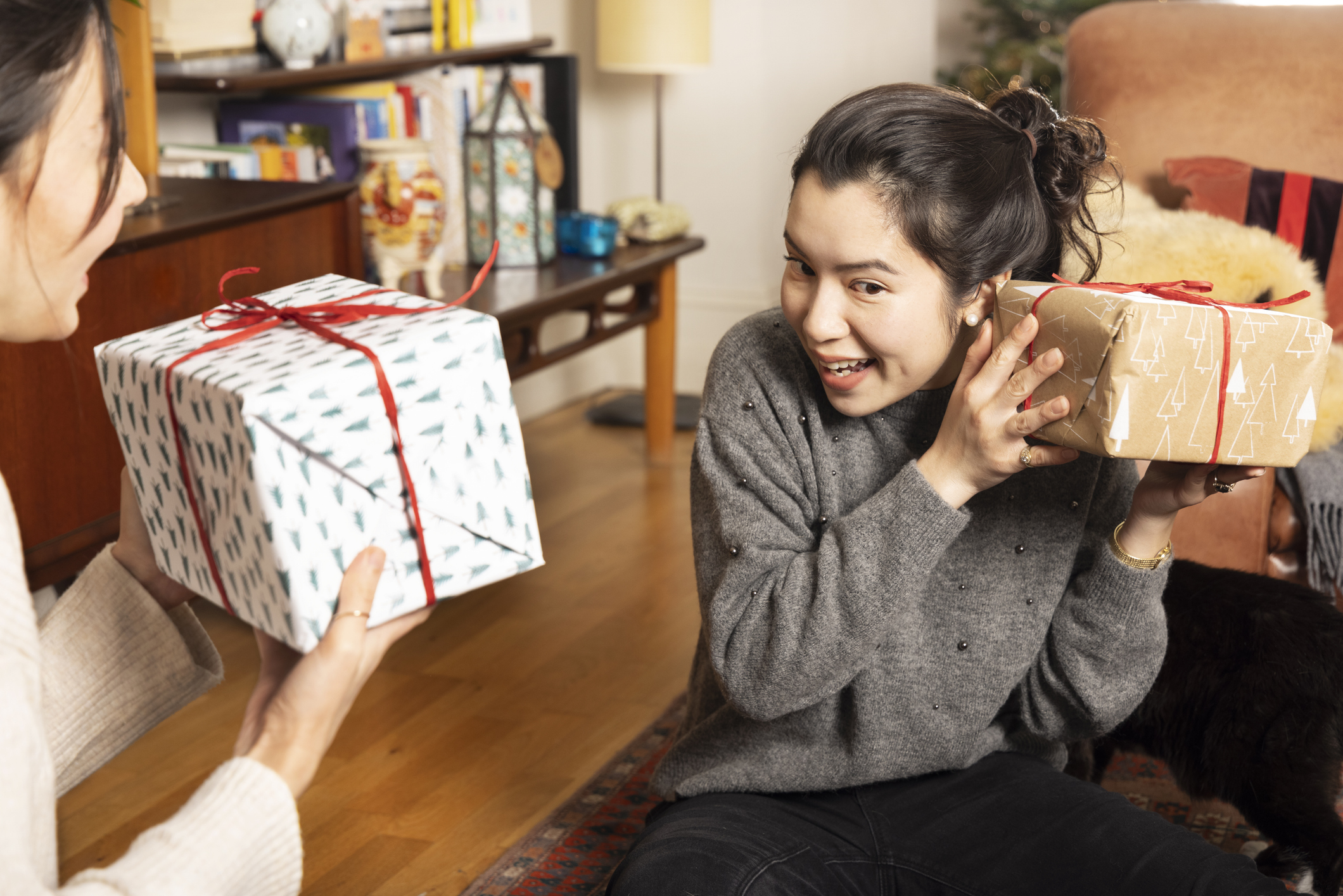 Woman shakes Christmas present to check what is inside.