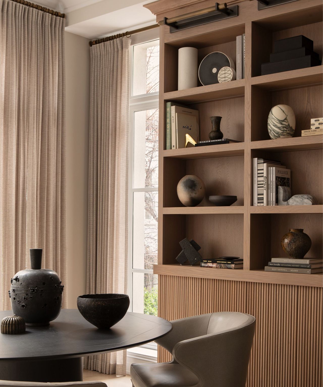A dark, moody dining room with built-in wooden shelving and a small round table