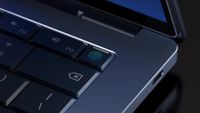 A screenshot from the promotional launch video of Google's Googlebook, showing a close-up view of the corner of the laptop and its power button, with a built-in fingerprint reader