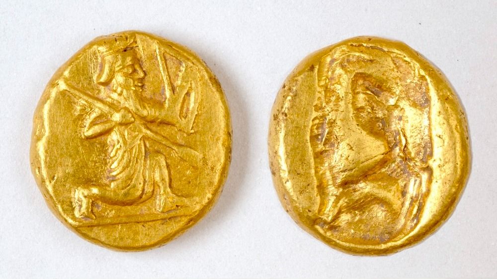 The front and back sides of a gold coin featuring the image of an archer. 