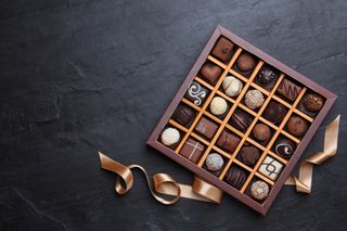 A brown box of chocolates on a slate surface.
