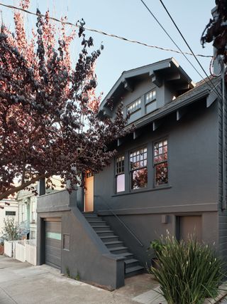 Exterior front view of the Edmonds + Lee house with dark grey walls and stairs leading to the wooden front door