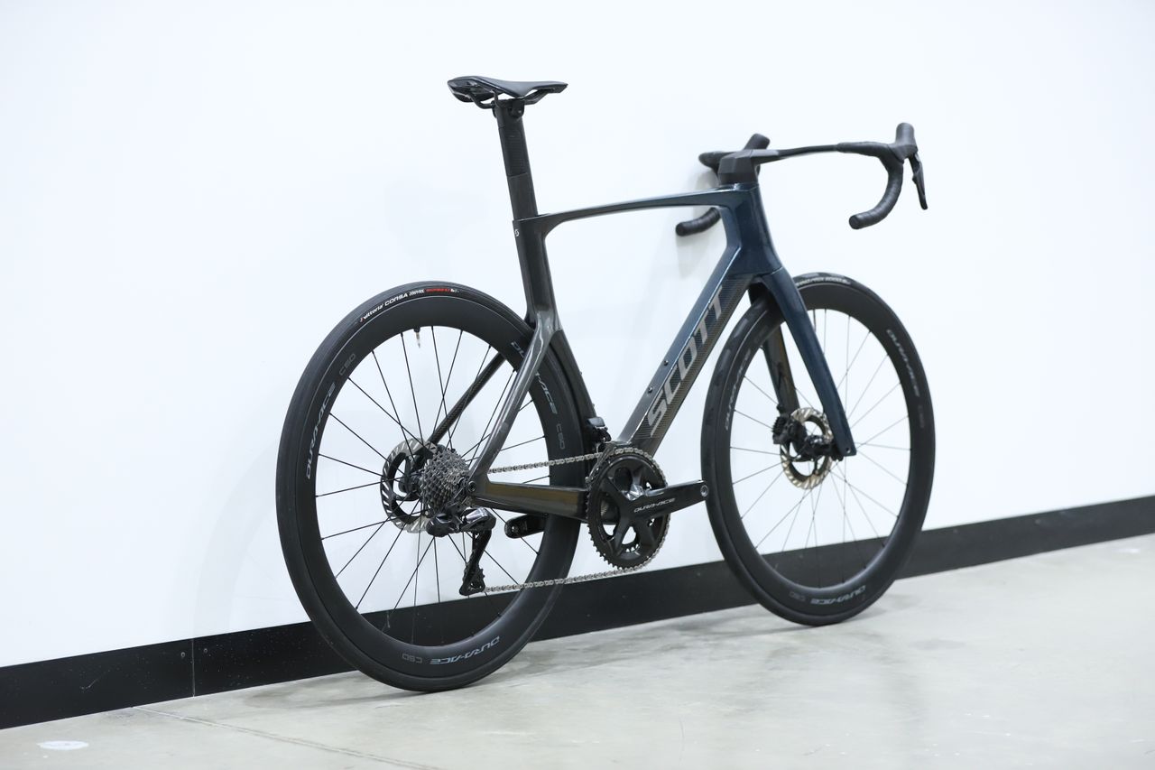 A blue Scott Foil RC Pro stands against a white wall