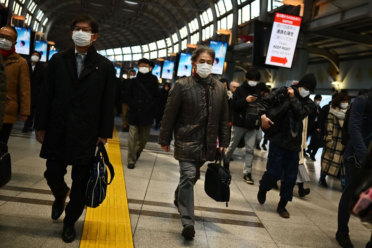 Mask-clad commuters make their way to work during morning rush hour at the Shinagawa train station in Tokyo on February 28, 2020. - Tokyo&amp;#039;s key Nikkei index plunged nearly three percent at th