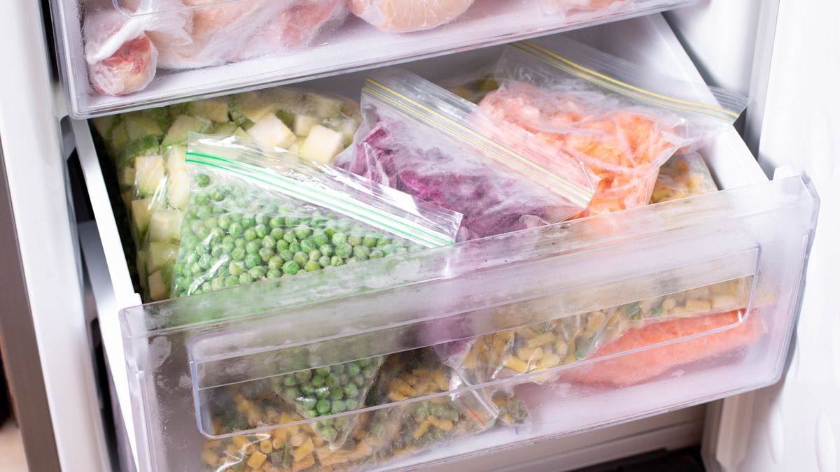 An open freezer with a drawer pulled out, filled with frozen produce