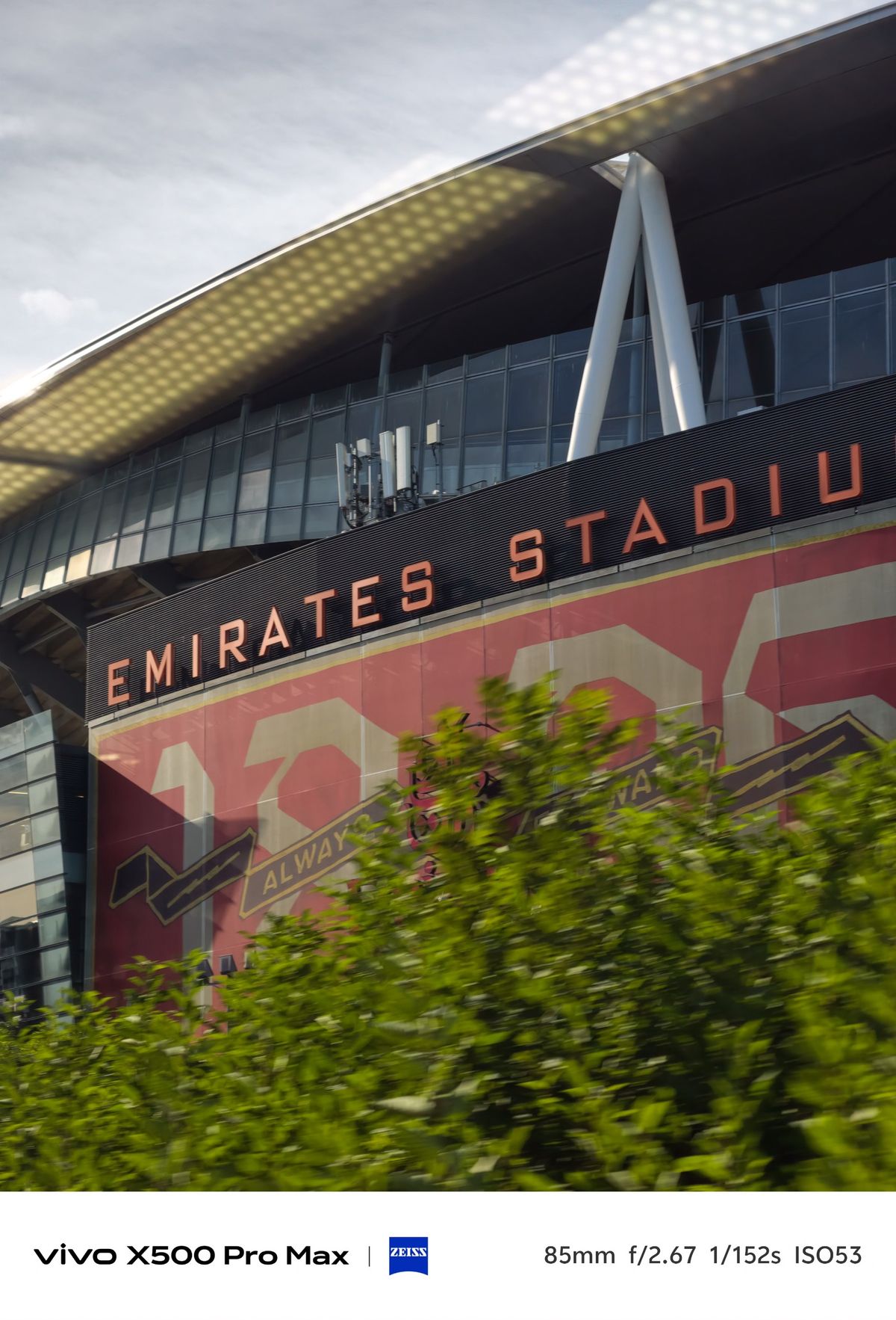 Exterior of Emirates Stadium in London, with the stadium name and red Arsenal graphics visible beneath the roof.