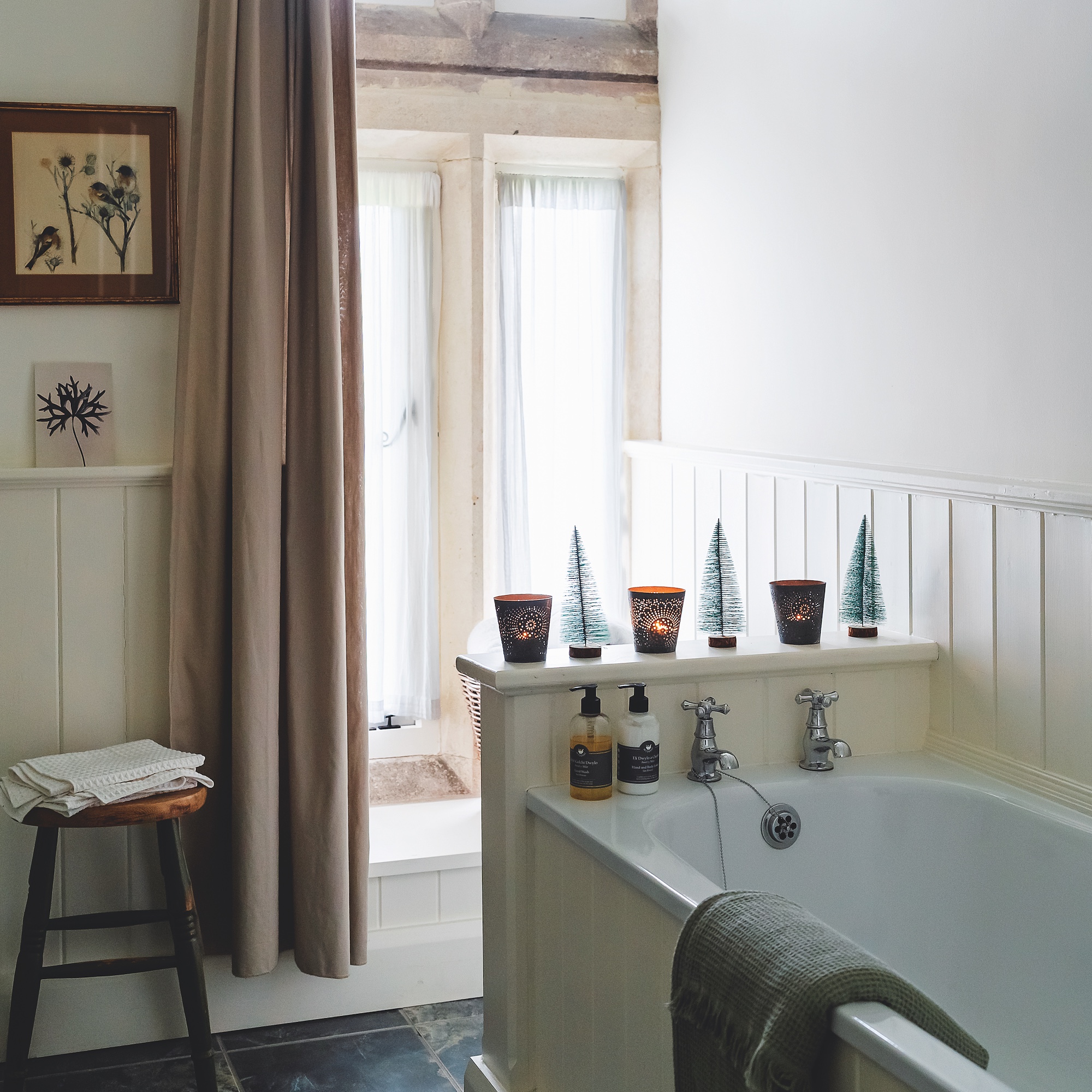 neutral bathroom with cream linen curtains and white bath