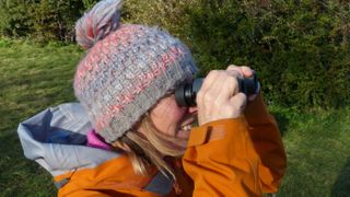 Woman wearing beanie hat using binoculars