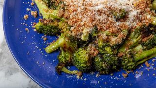 overhead shot of a blue plate loaded with roasted broccoli topped with caesar breadcrumbs