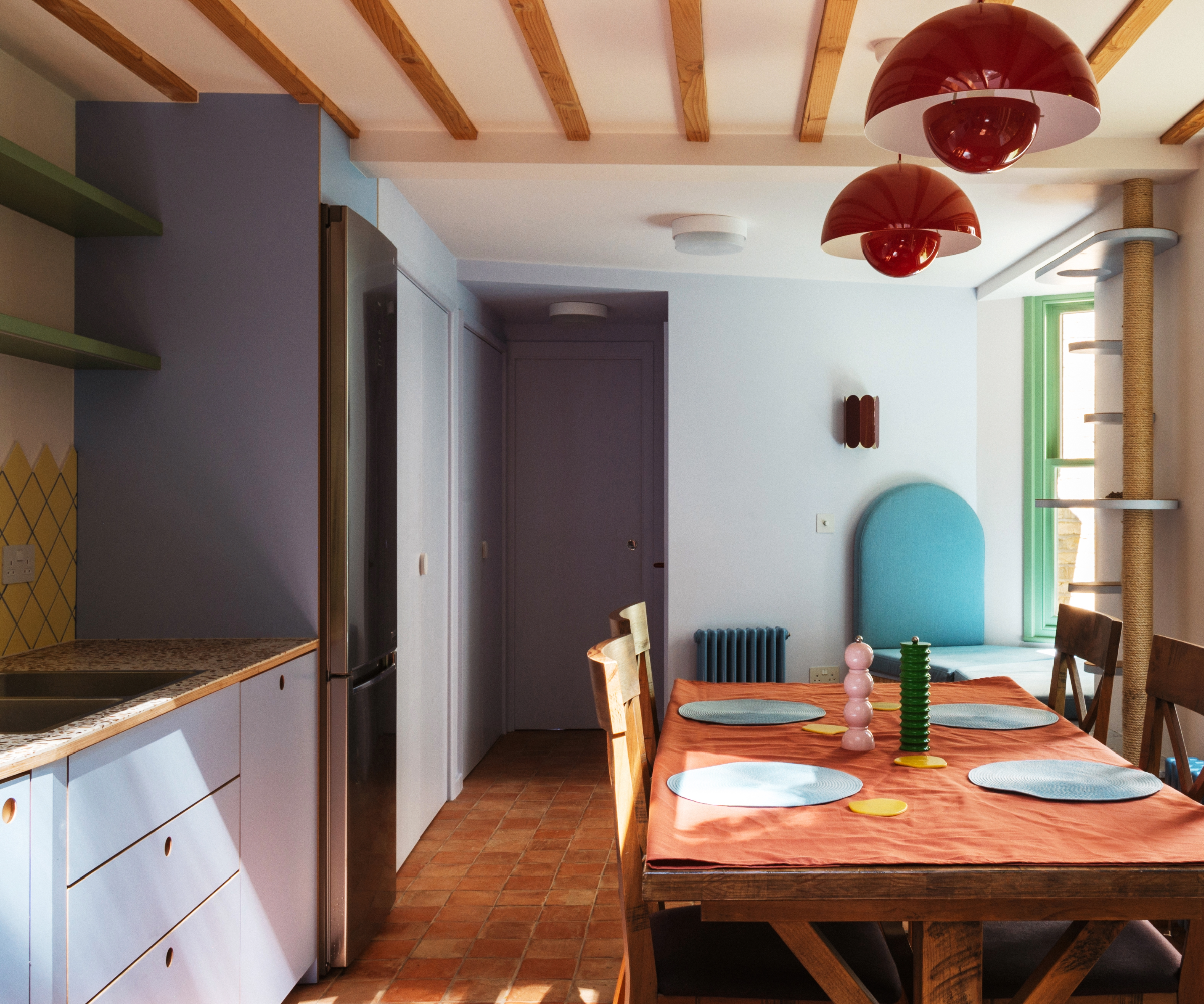 Kitchen with lilac cabinets, light blue walls, wooden beams in ceiling and red pendant lights