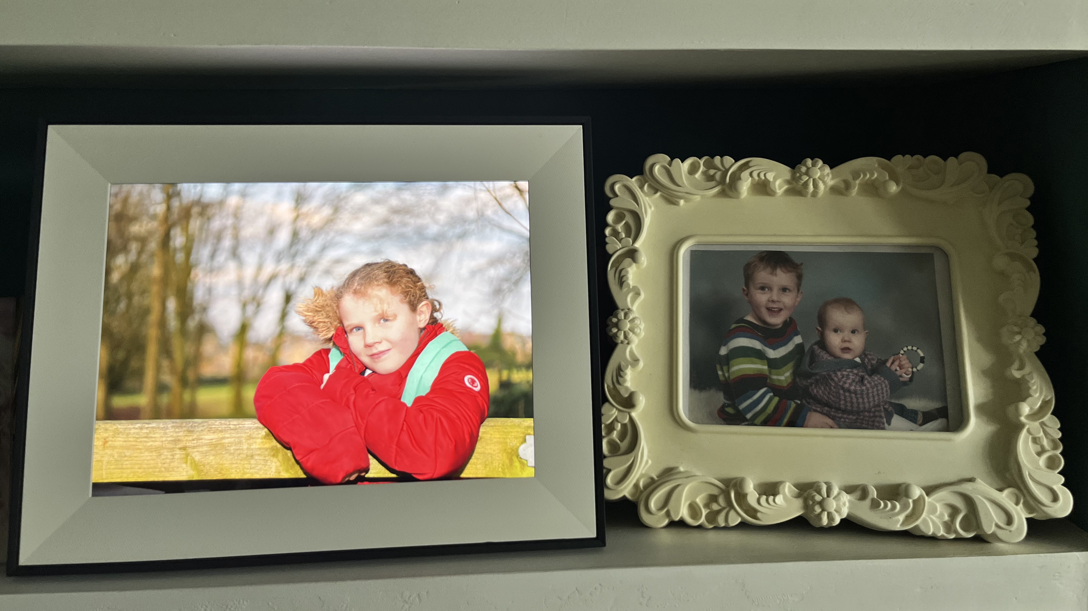 Aura Aspen digital photo frame on bookshelf with regular framed photographs